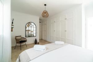 a white bedroom with a bed and a chair at Sweet Inn - Villa La Sala in Marbella