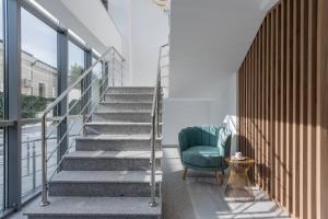 un escalier avec une chaise verte dans une chambre avec fenêtres dans l'établissement Aparthotel Pietroasa, à Buzău