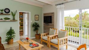 ein Wohnzimmer mit einem Balkon und einem TV in der Unterkunft Cape Cottages in Bergvliet