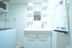een witte badkamer met een wastafel en een spiegel bij River Side Namba 400 in Osaka