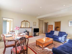 a living room with a blue couch and a table at The Garden Flat at Holbecks House in Hadleigh