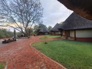 a pavilion with a thatched roof and a brick path at Milkwood Valley Lodge, Mabalingwe in Bela-Bela