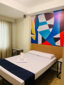 1 dormitorio con 1 cama con una pintura en la pared en Sultana Ysabella Hotel and Event en Manila