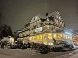 a large house with lights on in the snow at Parkhotel Pyrmont in Bad Pyrmont