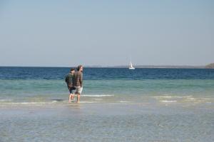 two people walking in the water on the beach at Bungalows Ostseequelle in Hohenkirchen