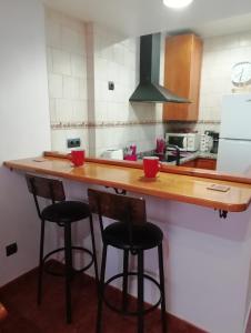 a kitchen with a counter with three bar stools at CA MARTÍN 2 in Benifallet