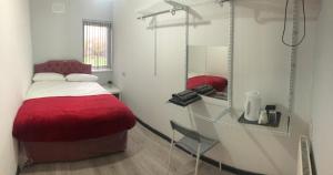 a bedroom with a red bed and a mirror at Queens b n b in Birmingham
