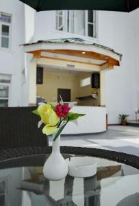 un jarrón blanco con flores sentado en una mesa en The Grand Mamta, en Srinagar