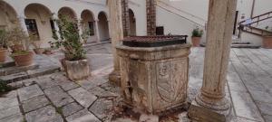 een oude stenen pilaar op een binnenplaats met potplanten bij Dormire nel Castello in Pitigliano