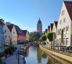 Ferienhaus in der Altstadt Memmingen Allgäu Bahnhofsnah في ميمينجين: نهر في مدينة بها مباني وكنيسة