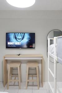 einen TV an einer Wand über einem Schreibtisch mit zwei Stühlen in der Unterkunft Dragonfly Apartments and Transient House in Bacoor