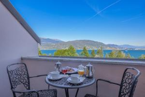 een tafel en stoelen op een balkon met uitzicht op het water bij Hotel Simplon in Baveno