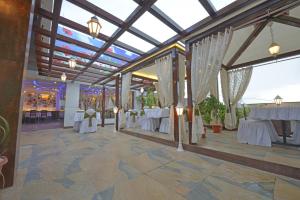 un salón de banquetes con mesas blancas y cortinas blancas en Hotel JP International en Aurangabad