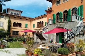 a building with a patio with tables and umbrellas at Villa Colle Olivi in Pescia