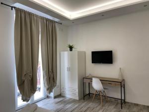Zimmer mit einem Schreibtisch, einem TV und einem Stuhl in der Unterkunft Room27 in Taranto