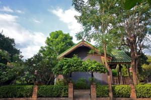 une petite maison avec une clôture et des arbres dans l'établissement Thai Thai Sukhothai Resort, à Sukhothaï
