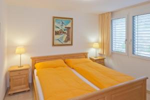 ツェルマットにあるCasa Collinettaのベッドルーム1室(黄色いシーツとランプ2つ付)