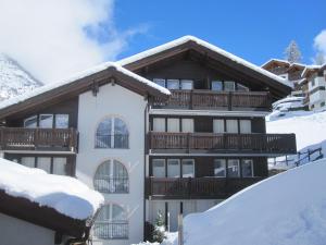 un gran edificio con nieve en el suelo en Casa Collinetta en Zermatt