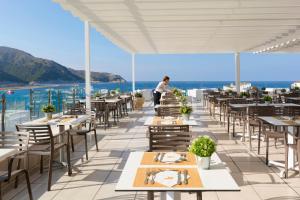 un restaurante con mesas y sillas con el océano en el fondo en HSM Regana - Adults only, en Cala Ratjada