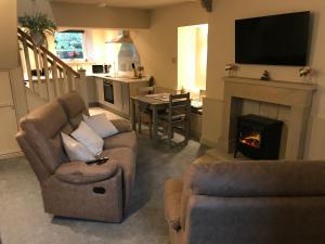 a living room with two couches and a fireplace at Bridge Cottage in Cowling