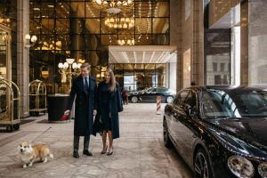
a man and woman walking down the street with a dog at The St. Regis Moscow Nikolskaya in Moscow
