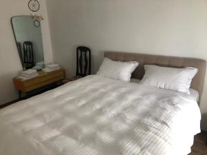 a bedroom with a large bed with white sheets and a mirror at Ethno House inn Tianeti in Tʼianetʼi