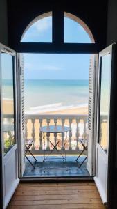 eine offene Tür zu einem Balkon mit Meerblick in der Unterkunft La Madelon Front de mer in Villers-sur-Mer