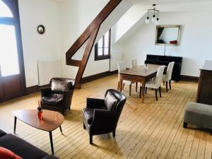 ein Wohnzimmer mit einem Tisch, Stühlen und einem Klavier in der Unterkunft La Madelon Front de mer in Villers-sur-Mer