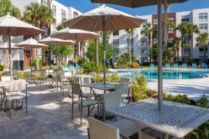 an outdoor patio with tables and chairs with umbrellas at Four Points by Sheraton Orlando Convention Center in Orlando
