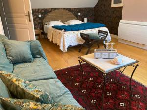 a living room with a bed and a couch and a table at Chambres d'hôtes Le Relais de la Perle in Le Vernois