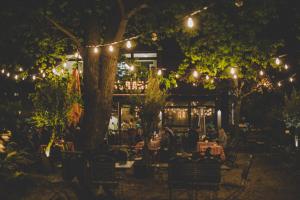un restaurante con mesas y sillas bajo los árboles por la noche en Hotel Luis, en Regensburg