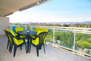 a balcony with a black table and yellow chairs at UHC Village Park Apartments in Salou