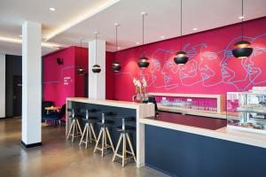 a restaurant with a pink wall with bar stools at sylc. Apartmenthotel – Serviced Apartments in Hamburg