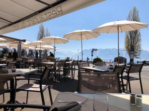 a group of tables and chairs with umbrellas at Hôtel du Port in Lausanne
