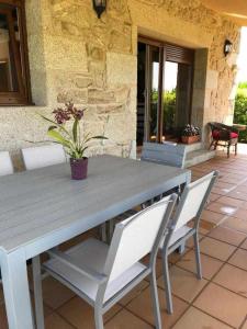 une table et des chaises en bois avec une plante en pot sur une terrasse dans l'établissement Cubelas Porto do Son, à Porto do Son