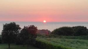 een zonsondergang over de oceaan met de zon aan de horizon bij Cubelas Porto do Son in Porto do Son