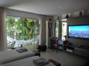 a bedroom with two beds and a large window with a television at Bangalô no alto da colina no Villas do Pratagy - Maceió in Maceió