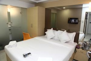 um quarto de hotel com uma grande cama branca e uma televisão em Hotel Lucky Galaxy em Mumbai