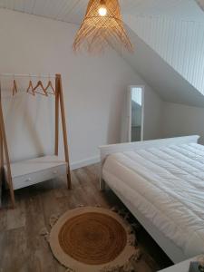 Un dormitorio blanco con una cama y una silla. en Esprit Mer classé - Wifi - Centre, en Auray