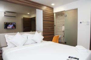 a bedroom with a large white bed and a bathroom at Hotel Lucky Galaxy in Mumbai