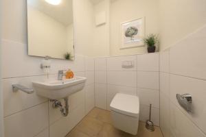 uma casa de banho branca com um lavatório e um WC em Ferienwohnung Quartier HOHE GEEST 12 em Cuxhaven