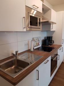 eine Küche mit einer Spüle und einer Mikrowelle in der Unterkunft Ferienwohnung Quartier HOHE GEEST 12 in Cuxhaven