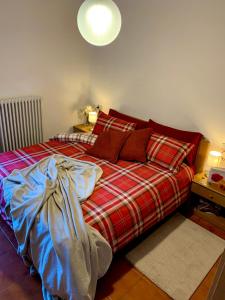 una camera con un letto con una coperta rossa a scacchi di Cima de’ Piazzi Apartment a Isolaccia