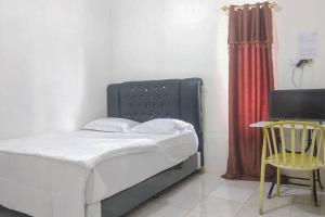 a bedroom with a bed and a table and a chair at Nayla Homestay Jambi Mitra RedDoorz in Kayu Aro