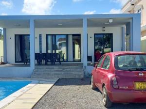 a red car parked in front of a house at Idyllic Villa in Pereybere with Private Pool in Pereybere