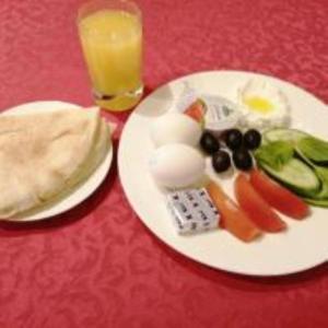 a plate of eggs and vegetables and a glass of orange juice at Al Ramla Al Hamra Hotel in Taif