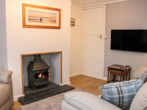 a living room with a fireplace and a tv at 1 Sarnwen Cottages in Llanymynech