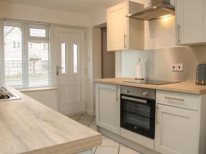 cocina con armarios blancos y encimera en 1 Sarnwen Cottages, en Llanymynech