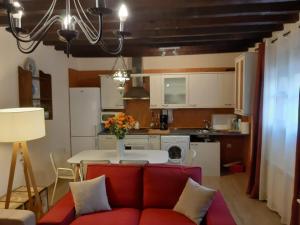 a living room with a red couch and a kitchen at Casas Recuero in Chinchón