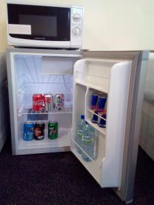 an open refrigerator with a microwave on top of it at Britannia Inn Hotel in Ilford